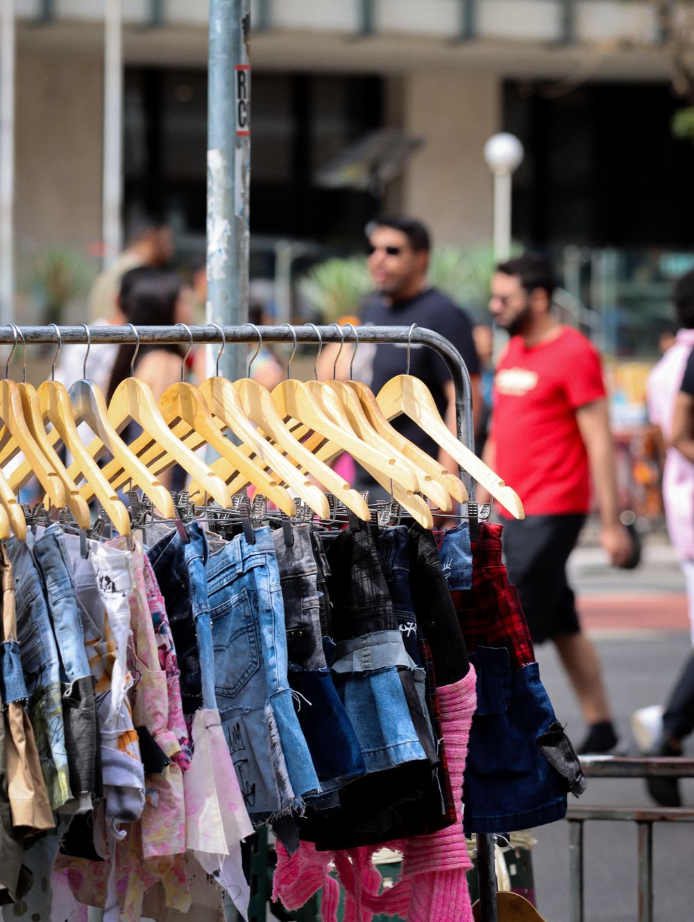 A vibrant outdoor market display featuring denim clothes with pedestrians behind.